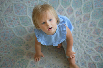 Naklejka premium childhood, babyhood and people concept. happy little baby girl sitting on floor at home. view from above