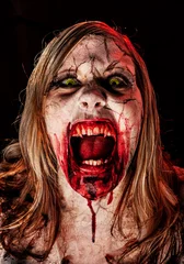 Fotobehang Studio portrait of a female vampire of zombie with open mouth, screaming and looking at camera © Stockis