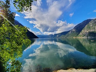 reflection of the sky and mountains in the blue water of the fjord - Eidfjord