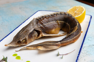 smoked fish sturgeon in a plate with lemon