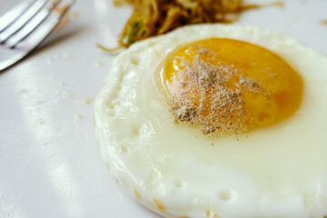 Close up of fried egg in white plate with salt and pepper