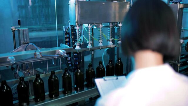 Giovane dottoressa con camice bianco sta guardando la qualit&agrave; della produzione nella fabbrica 