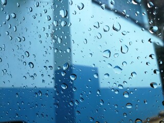 Raindrops on window and blue building in the background.
