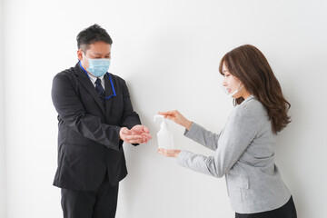アルコール消毒をお願いするビジネスパーソン