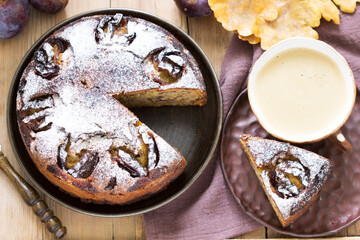 Plum pie with nuts and chocolate on a wooden background. Rustic style.
