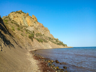 Fototapeta na wymiar Summer seascape with rocks on the coast of crimea. view on cape in the sea, clear water, calm hot day.