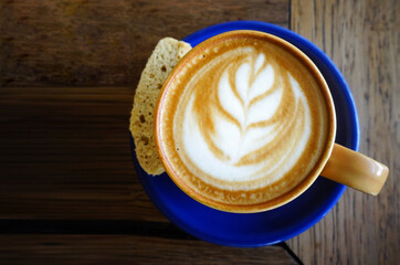 a cup of cappuccino with a slice of bread. top view on wooden table