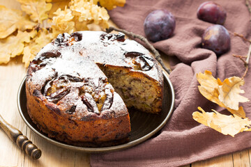 Plum pie with nuts and chocolate on a wooden background. Rustic style.