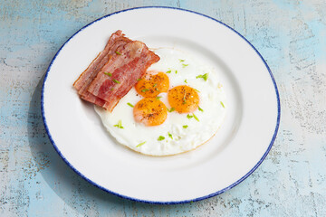 three fried eggs with bacon in a plate
