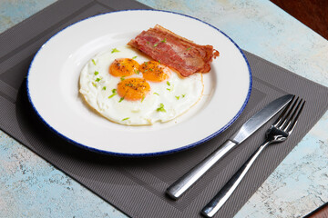 three fried eggs with bacon in a plate
