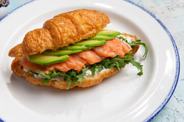 croissant with salmon and avacado in a plate