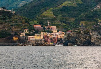 Nice panoramic view of Vernazza in the Cinque Terre coastal area from the sea. The colourful houses with the famous Church of Santa Margherita d'Antiochia are surrounded by vineyards on the hillside.