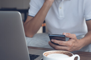 Casual business man using mobile phone online working on laptop computer in coffee shop