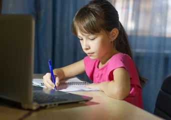 Fotobehang Online onderwijs op afstand. Een schoolmeisje studeert thuis en maakt huiswerk via internet © Albert Ziganshin