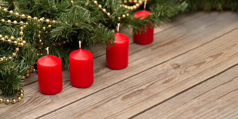 Christmas background. Branches of a Christmas tree with decorations and red candles on a wooden background.