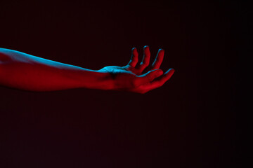 Antebrazo y mano rojo y azul en fondo oscuro