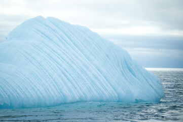 An icy white iceberg floats in the sea in the Arctic on Svalbard