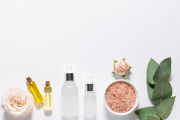 Set of natural Eco cosmetic supplements with rose flowers and eucalyptus twigs on white background with copy space for your design. Spa branding mock up.