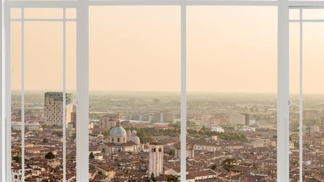 Brescia cityscape as seen from a white window while birds are flying at the sunset. It is seen the capitolium, cathedral of Saint Maria assunta and the tower