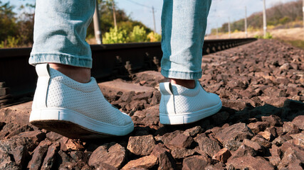 Female legs in jeans and white sneakers