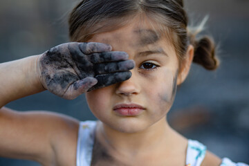 Girl with dirty face and hands after a wildfire