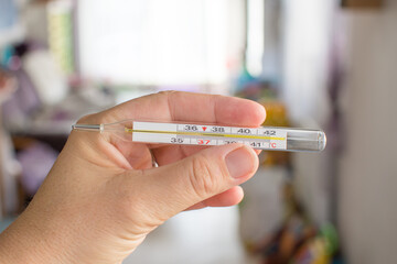 Glass mercury thermometer in human nand and high fever. Measuring temperature sick person. Stay home coronavirus concept.