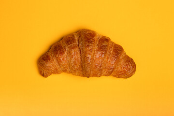 Fresh croissant isolated on yellow background, top view, close up, copy space