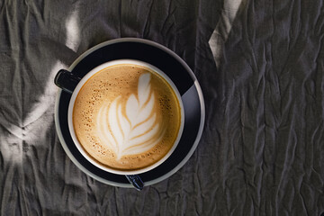 Coffee with latte art on grey tablecloth, top view