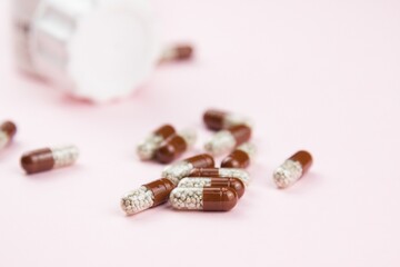 Brown soluble capsules on pink. Herbal drugs. Alternative medicine in capsule