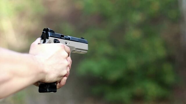 shooter shoots a pistol, close-up, focus on the pistol, soft focus