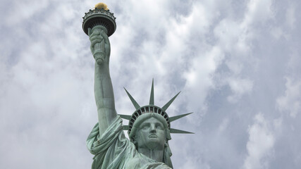 Close up shot of the Statue of Liberty in New York City with dramatic clouds behind.