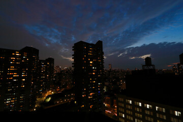 Fototapeta na wymiar Blick auf einen Wolkenkratzer von Harlems bei Nacht, große Silhouetten und ein bewölkter Himmel. Das Stadtlicht leuchtet im Dunst.