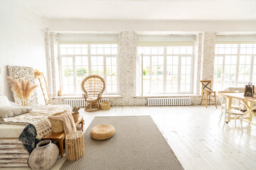 Large spacious room with a trendy loft design of sitting area. huge windows and stylish wicker light furniture inside. an abundance of ethnic decor