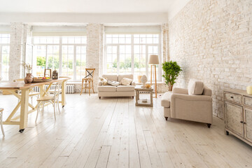 Large spacious room with a trendy loft design of sitting area. huge windows and stylish wicker light furniture inside. an abundance of ethnic decor