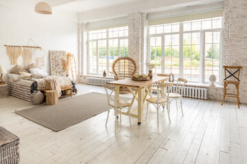 Large spacious room with a trendy loft design of sitting area. huge windows and stylish wicker light furniture inside. an abundance of ethnic decor