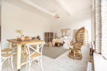 Large spacious room with a trendy loft design of sitting area. huge windows and stylish wicker light furniture inside. an abundance of ethnic decor