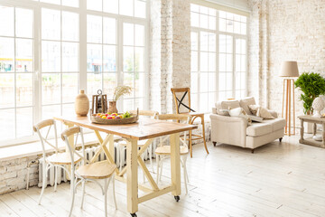 Large spacious room with a trendy loft design of sitting area. huge windows and stylish wicker light furniture inside. an abundance of ethnic decor