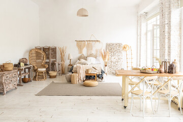 Large spacious room with a trendy loft design of sitting area. huge windows and stylish wicker light furniture inside. an abundance of ethnic decor