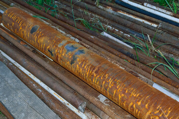 close-up - there are rusty iron pipes on the ground through which grass grows
