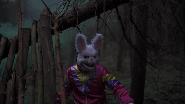 Man with Halloween bunny mask sneaks with smoke grenade through the forest