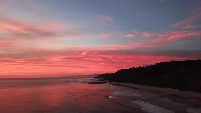 Red romantic sunset in the horizon of Santa Teresa Costa Rica - aerial