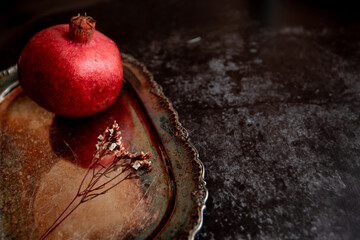 fresh pomegranate on a beautiful vintage tray on a dark background. beautiful still life