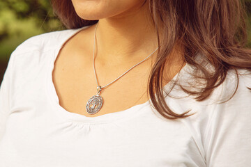 Female neckline wearing tiny silver chain with silver pendant in the shape of tree in mandala