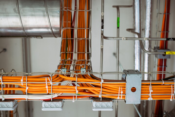 Electrical conduits system and metal pipeline installed on building ceiling, orange wires