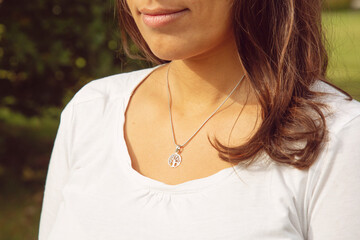Female neckline wearing tiny silver chain with silver pendant in the shape of tree in mandala