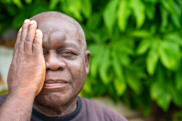 image of african aged man, hand covering one eye- eye health concept