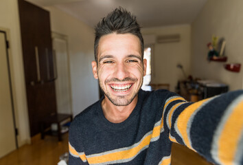 Handsome caucasian man taking a selfie portrait indoor at home - Happy guy smiling at the camera.