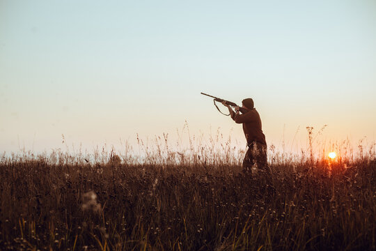 Hunter's dark silhouette with blue sky and red sun - photo with selective focus