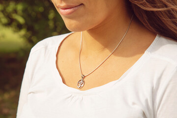 Female neckline wearing tiny silver chain with silver pendant in the shape of om in mandala