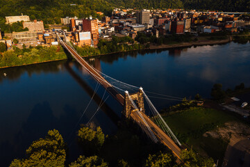 Fototapeta na wymiar This is an aerial view of the historic Wheeling Suspension Bridge that carries the National Road over the still blue waters of the Ohio River in Wheeling, West Virginia.